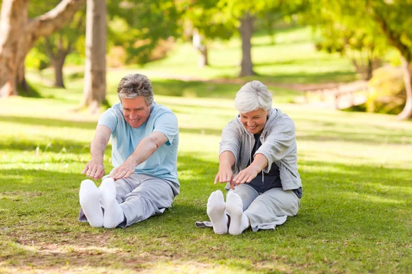 Äldre par gör sina sträckor i parken — Stockfoto