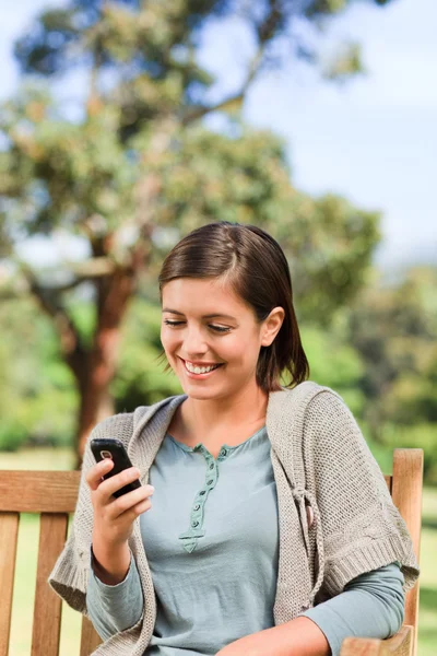 Mladá žena telefonují na lavičce — Stock fotografie