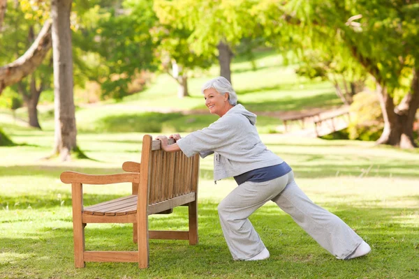 Starší žena, která dělá její úseky v parku — Stock fotografie