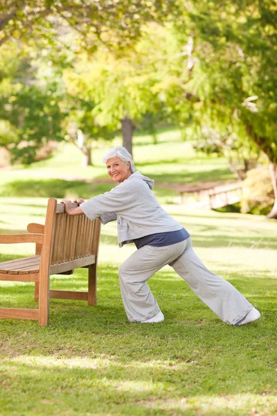 Senior vrouw doet haar strekt zich uit over het park — Stockfoto