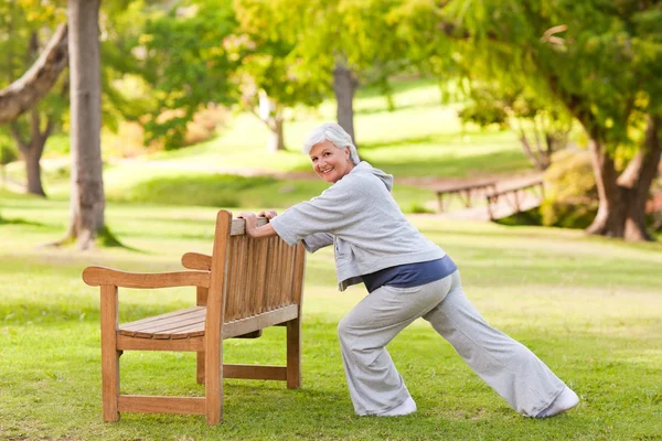 Старшая женщина делает растяжку в парке — стоковое фото