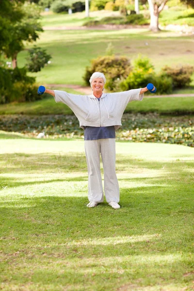 Зрелая женщина делает упражнения в парке — стоковое фото