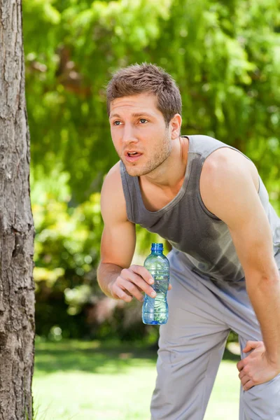 Sportovní muž pitné vody v parku — Stock fotografie