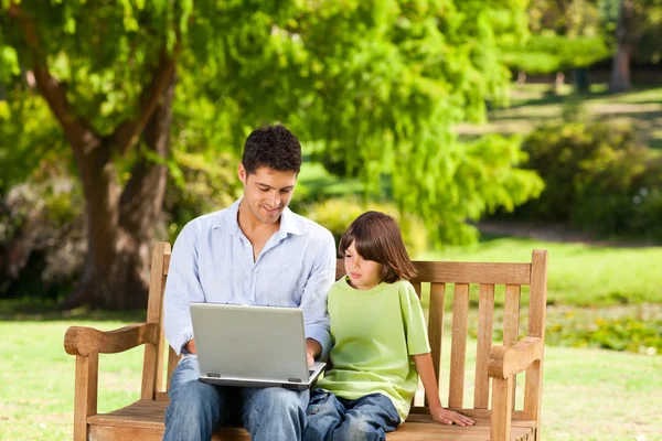 Сын с отцом смотрит на их ноутбук — стоковое фото