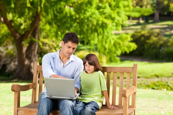 ลูกชายกับพ่อของเขา มองไปที่แล็ปท็อปของพวกเขา — ภาพถ่ายสต็อก