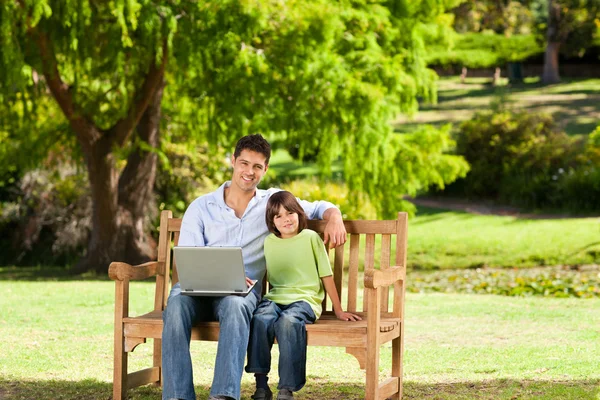 Far med sin son som tittar på deras laptop — Stockfoto