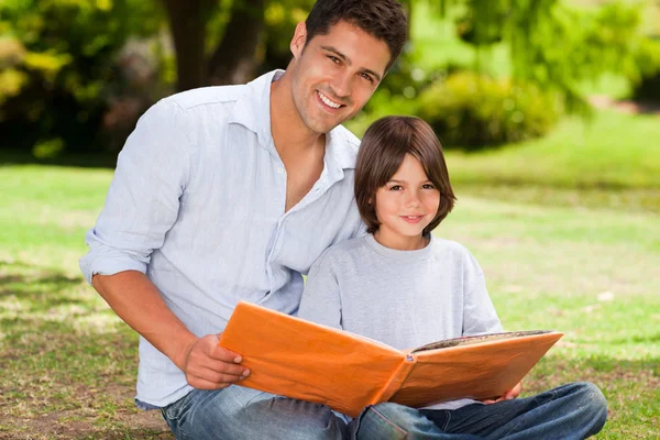 Hijo con su padre mirando su álbum de fotos —  Fotos de Stock
