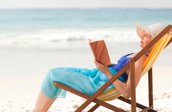 Elderly woman reading a book at the beach Stock Picture