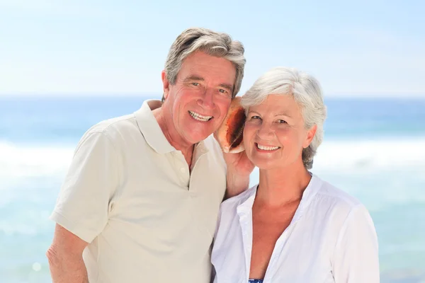 Retired couple listening to their shell Royalty Free Stock Images