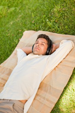 Young man listening to music in the park clipart