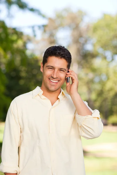 Yakışıklı adam parkta telefon ederek — Stok fotoğraf