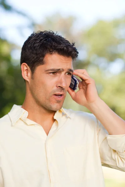 Handsome man phoning in the park — Stock Photo, Image