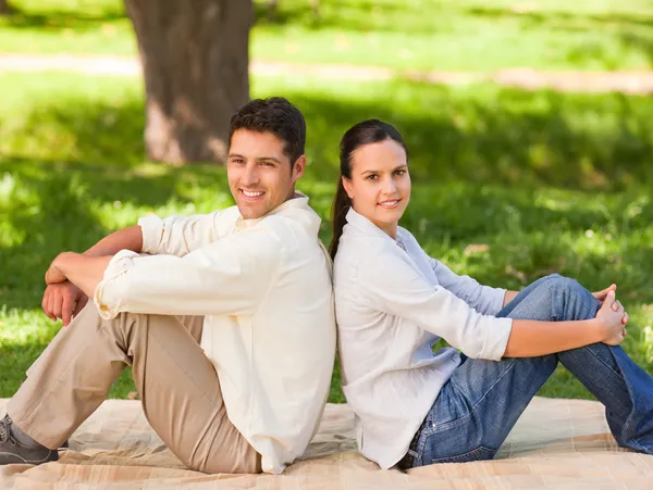 Par sitter rygg mot rygg i parken — Stockfoto