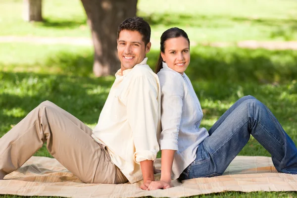 Par sitter rygg mot rygg i parken — Stockfoto