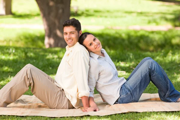 Älskare sitter rygg mot rygg i parken — Stockfoto
