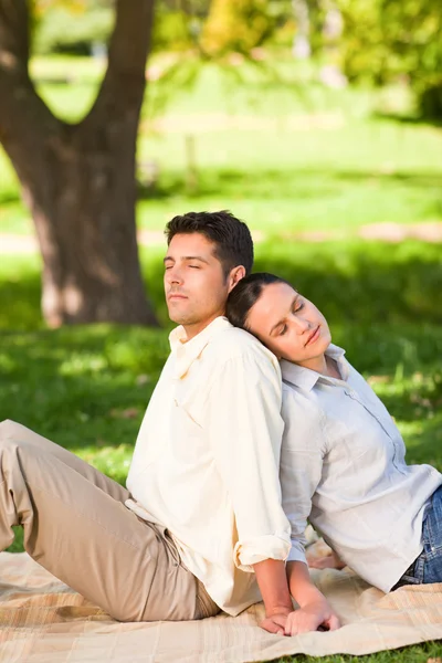 Älskare sitter rygg mot rygg i parken — Stockfoto
