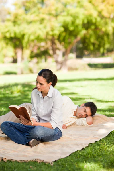Žena čte, zatímco její manžel spí — Stock fotografie