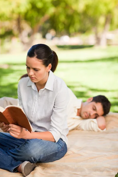 Vrouw leest terwijl haar echtgenoot is slapen — Stockfoto