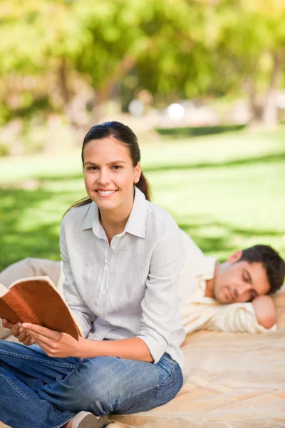 Mujer leyendo mientras su marido duerme — Foto de Stock