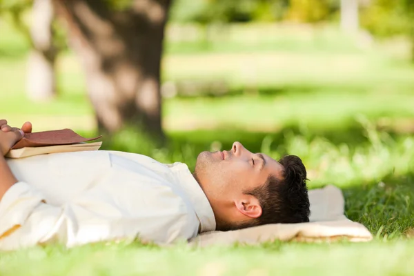 Чоловік лежить у парку зі своєю книгою — стокове фото