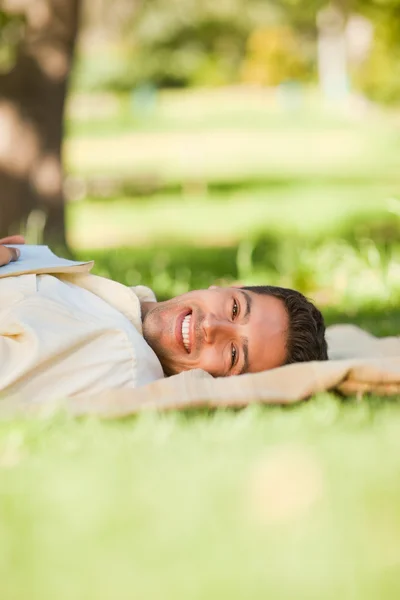 Un homme couché dans le parc avec son livre — Photo