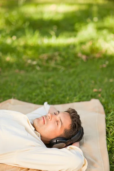 Young man listening to music in the park — Stock Photo, Image