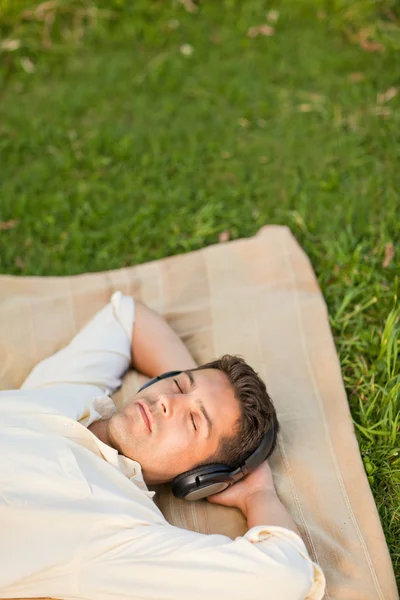 Ung mand lytter til musik i parken - Stock-foto