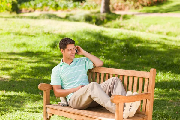 Muž s jeho telefonem na lavičce — Stock fotografie
