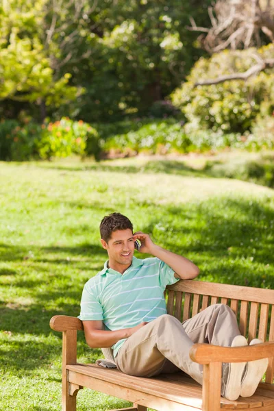 Muž s jeho telefonem na lavičce — Stock fotografie