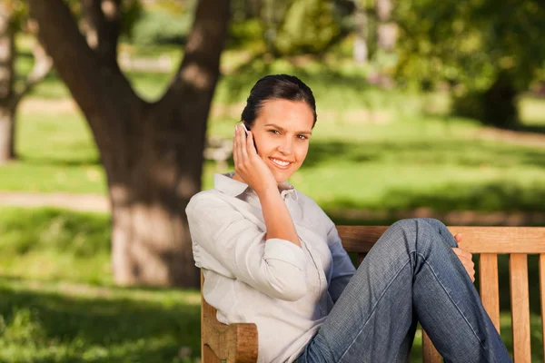 Young beautiful woman phoning on the bench — Stock Photo, Image