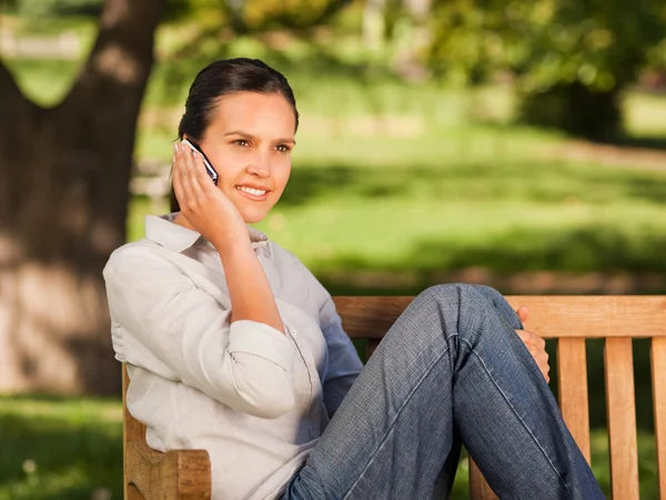 Mladá krásná žena telefonují na lavičce — Stock fotografie