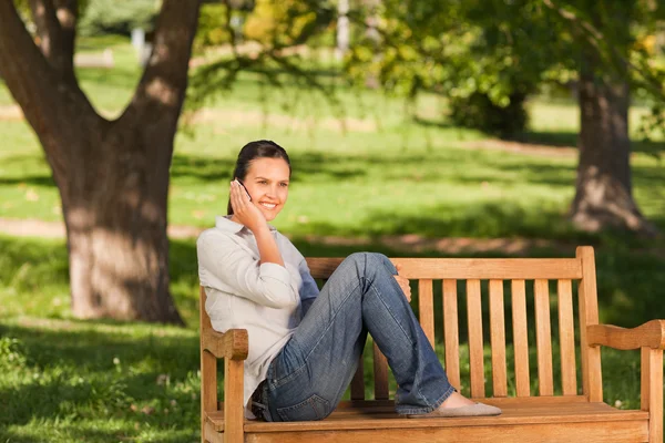 年轻漂亮的女人坐在板凳上打电话 — 图库照片