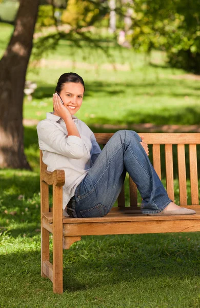 若い美しい女性がベンチに電話をかける — ストック写真