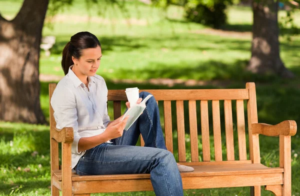 Jeune femme lisant sur le banc — Photo