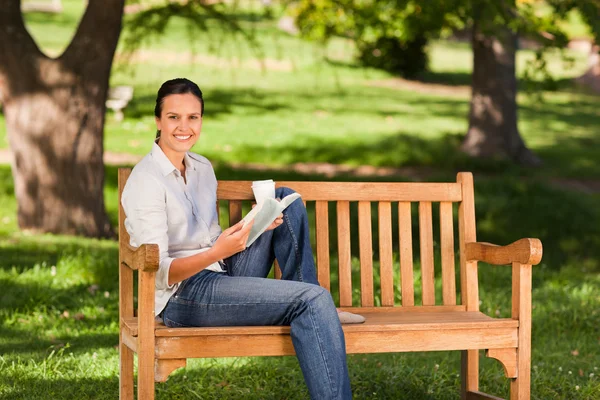 Молодая женщина читает на скамейке — стоковое фото