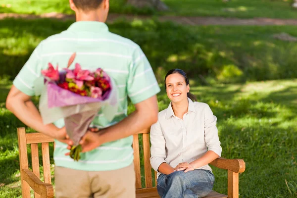 Ung man erbjuder blommor till sin fru — Stockfoto