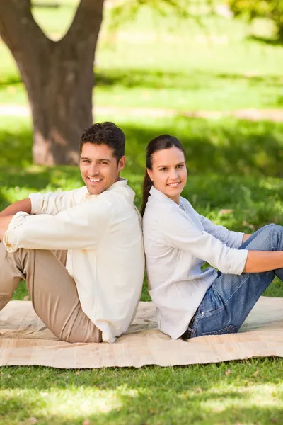 Couple sitting back to back in the park Royalty Free Stock Images