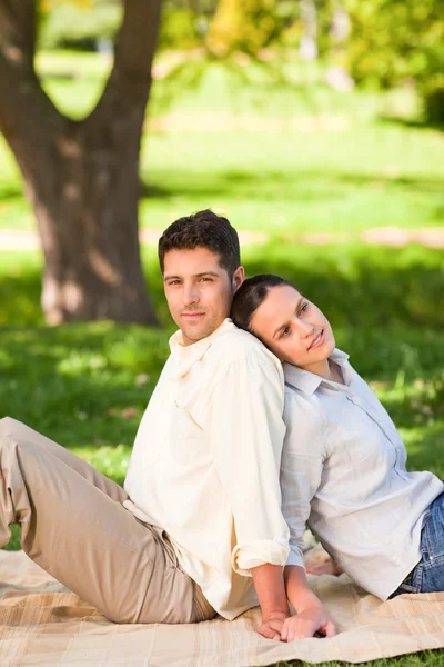 Lovers sitting back to back in the park Stock Photo
