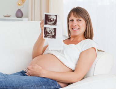 Close up of a pregnant woman holding her baby's ultrasound scan clipart