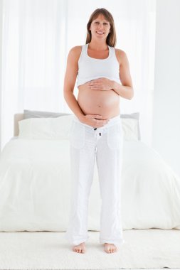 Beautiful pregnant female posing while standing clipart