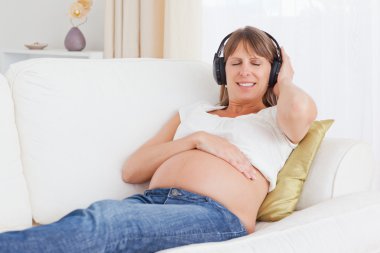 Happy pregnant woman listening to music clipart