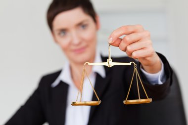 Serious businesswoman holding the justice scale clipart