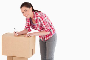 Beautiful woman writing on cardboard boxes with a marker while s clipart