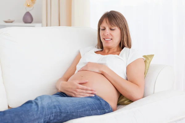 怀孕的女人躺在一张沙发上 — 图库照片