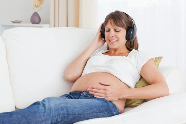 Улыбающаяся беременная женщина слушает музыку — стоковое фото
