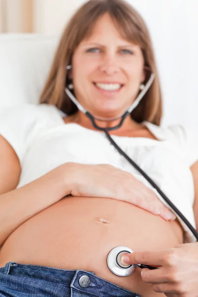 Szemközti nézet egy vonzó terhes nő használ egy fonendoszkóp — Stock Fotó