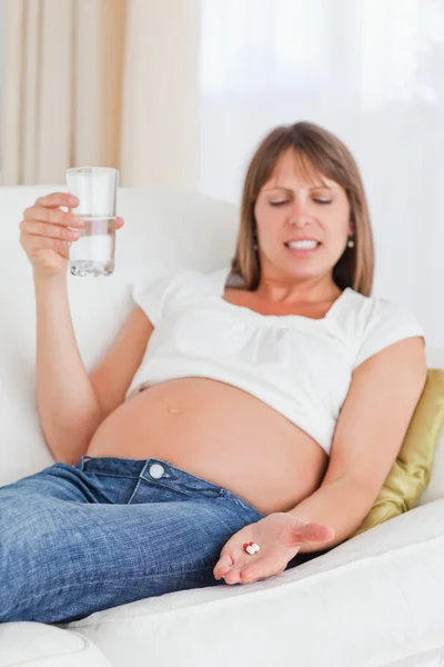 아름 다운 임신한 여자는 소파에 누워 있는 동안 약을 복용 — 스톡 사진