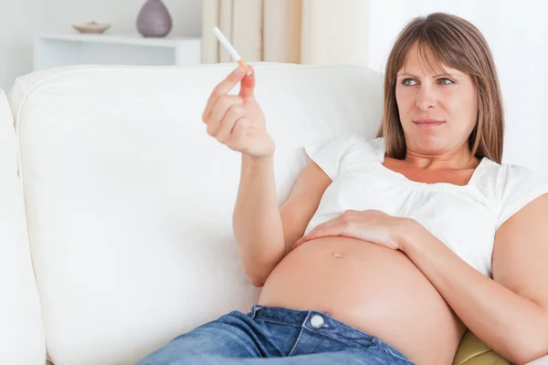 Aantrekkelijke zwangere vrouw die een sigaret te houden terwijl liggend op een s — Stockfoto