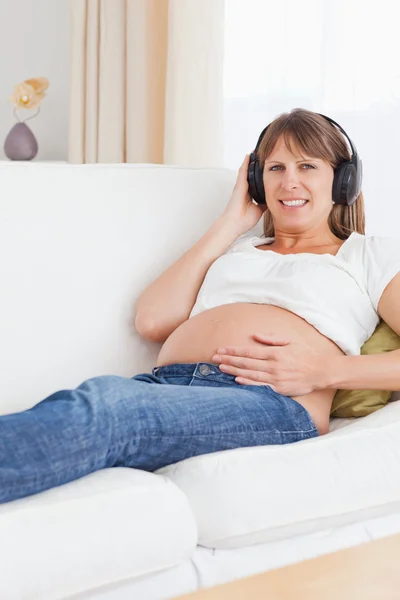 音楽を聴いて笑顔妊娠中の女性の肖像画 — ストック写真