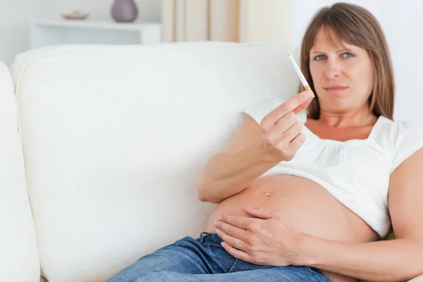 魅力的な妊娠中の女性、sof に横たわっている間タバコを保持 — ストック写真
